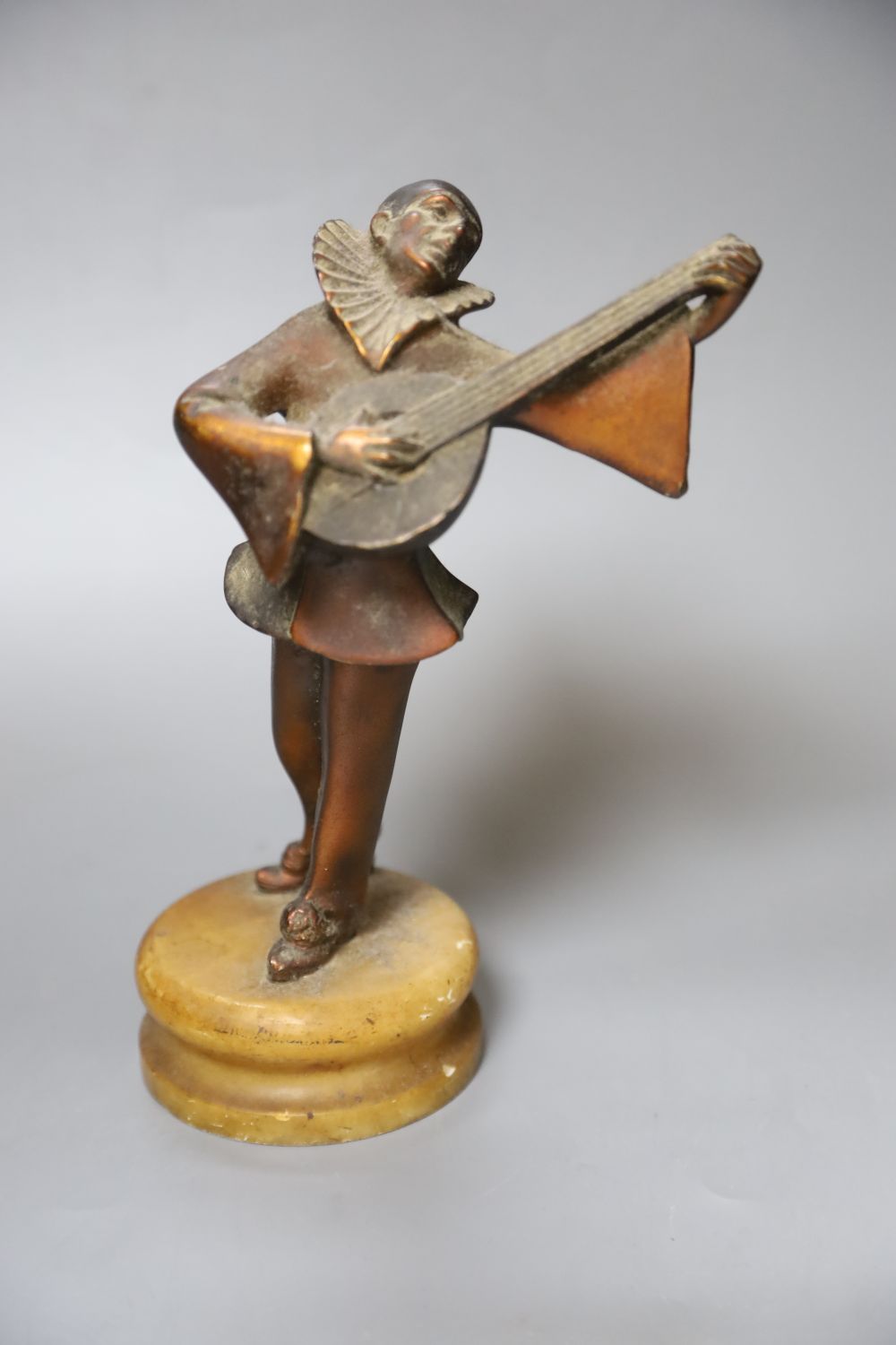 A 1930s Pierrot musician playing the lute, on alabaster plinth, height 23cm